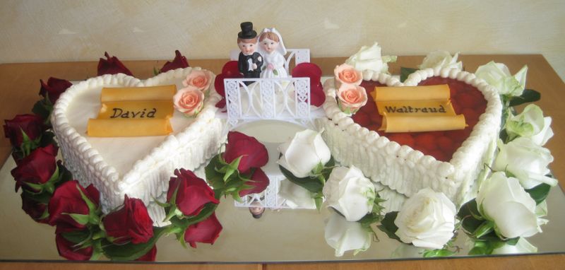 Hochzeitstorte mit Fruchtherz und Buttercremeherz mit Brautpaar und roten & weißen Rosenblüten